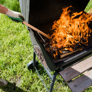 Man working to regulate temperature in a smoker