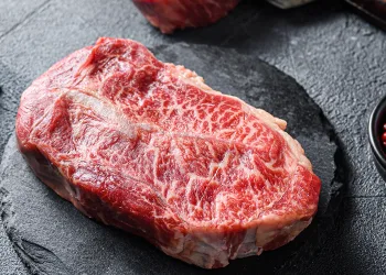 Raw blade steak on top of grey stone surface