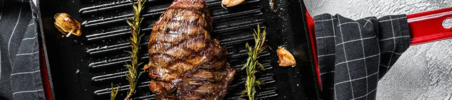 Top view of a roasted steak on a grilled red pan