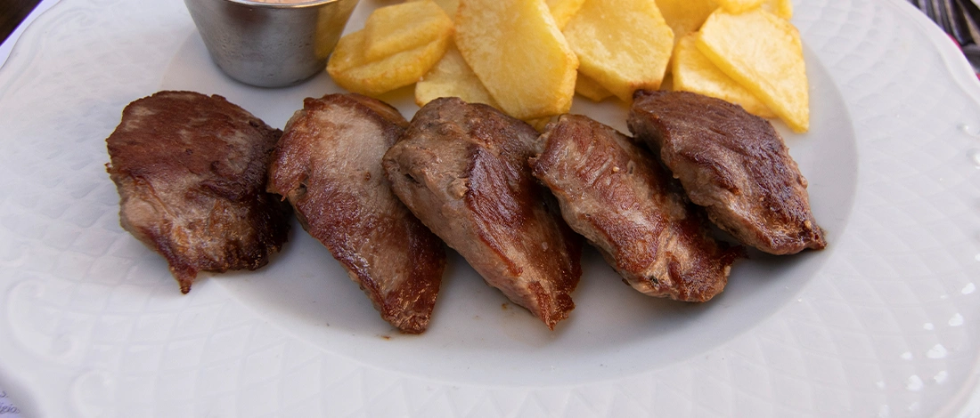 Cooked meet on plate sliced potatoes