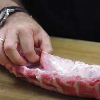 Hand trying to get the silverskin off from the ribs