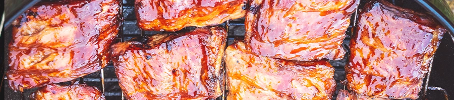 Top view of pork being cooked on charcoal grill