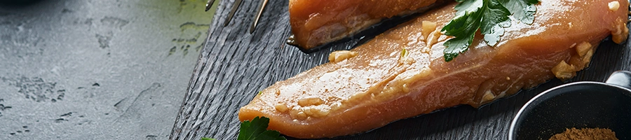 Close up image of honey garlic chicken breast on cutting board and marble top