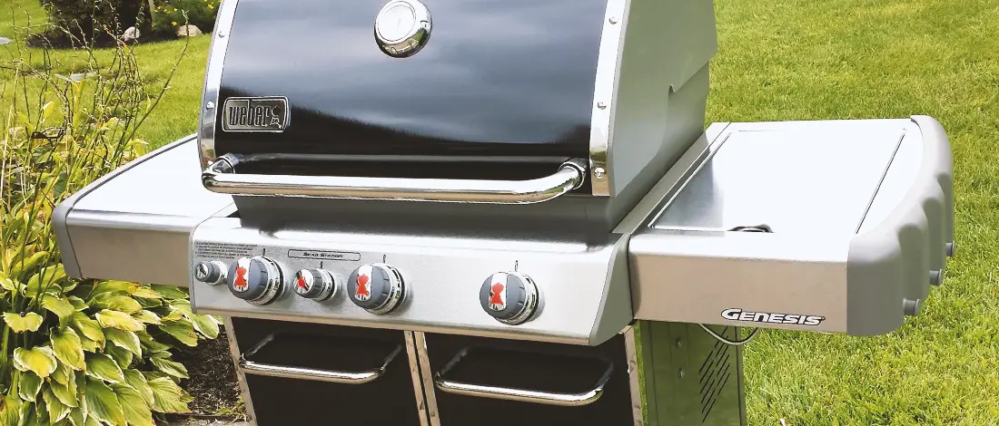 Weber grill outside a grassy backyard
