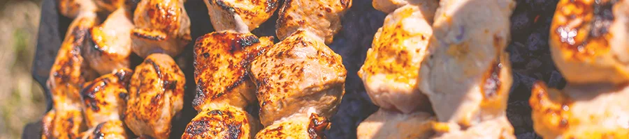 "Closeup shot of charred meat being smoked on a smoker