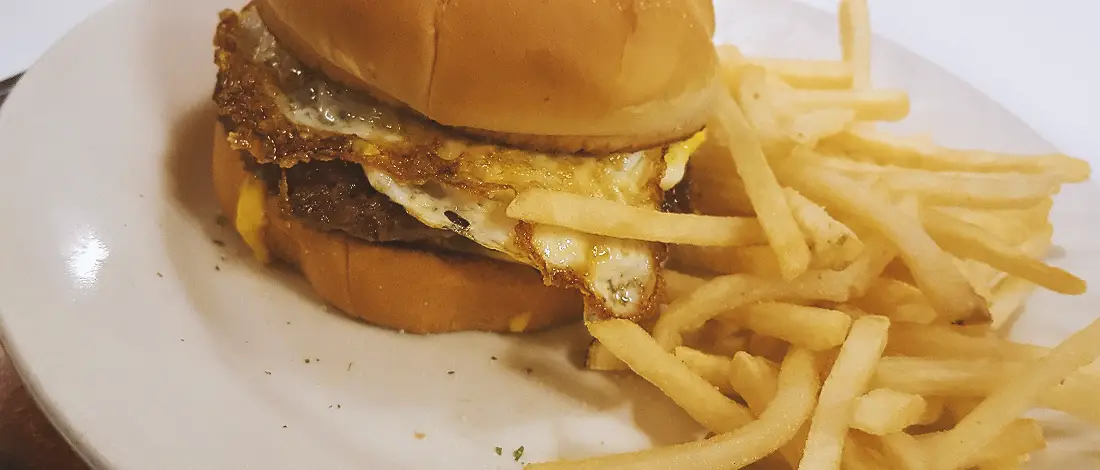 A steak burger with fries on a plate