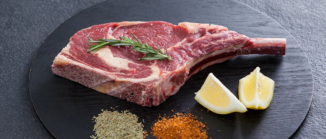 A huge raw meat on a plate with lemons