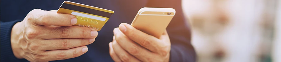 A person holding a mobile phone and a credit card