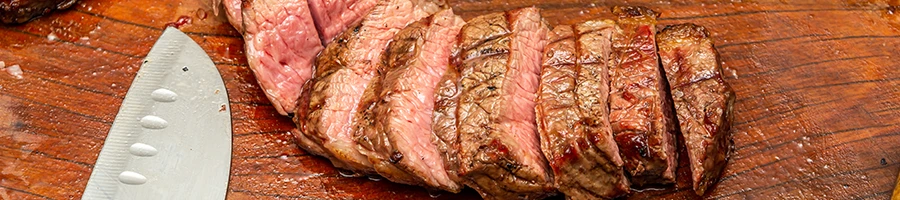 An image of a sliced steak on a wooden board