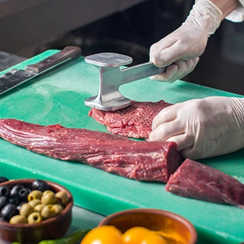 A person tenderizing ball tip steak