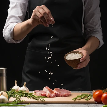 A chef sprinkling salt on top of a raw meat