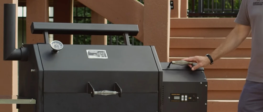 A man standing beside a Yoder smoker