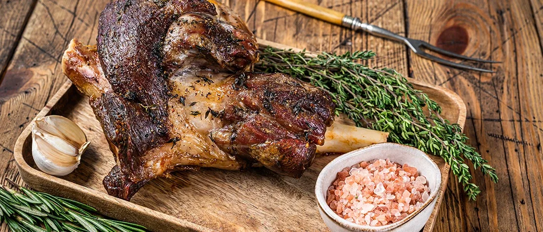 An image of cooked goat meat on a wooden plate