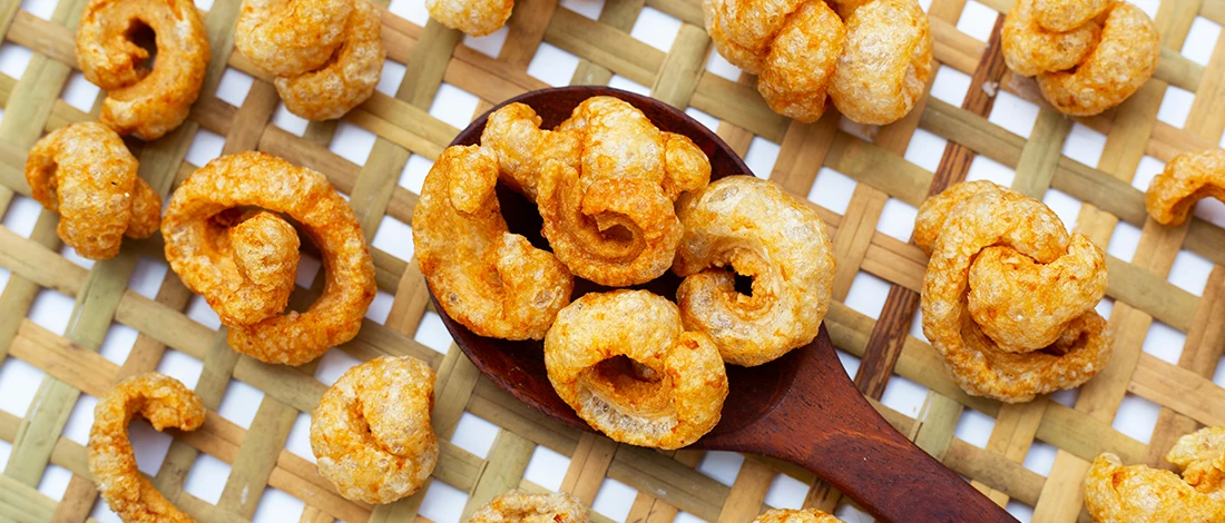 An image of pork rinds on top of a wooden spoon and basket