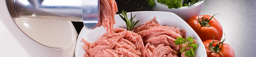 A close up image of ground meat coming out of a meat grinder