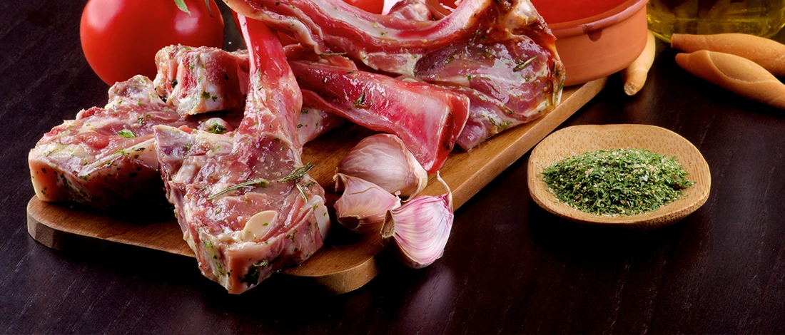 An image of raw lamb meat on a wooden board