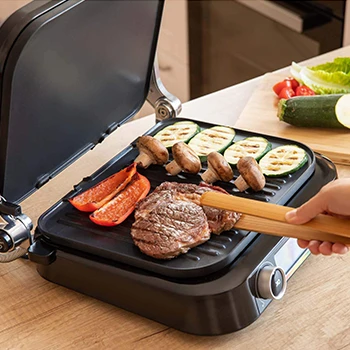 An image of a person grilling meat and vegetables using a contact grill