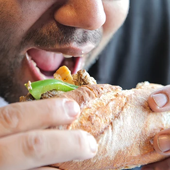 A man who is about to eat a Philly cheesesteak sandwich