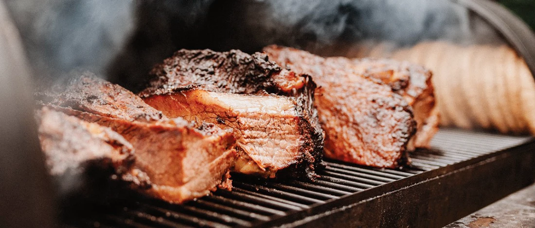 A close up shot of a meat being cooked inside a smoker