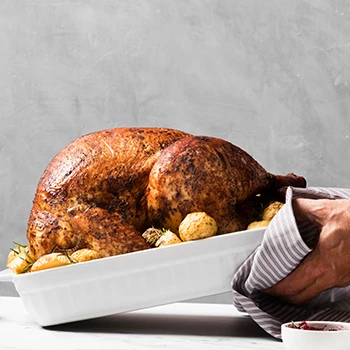 A person placing a turkey on a table to rest