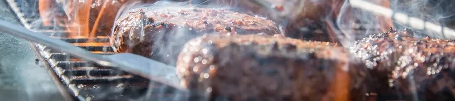 A close up shot of burger being grilled in a smoker