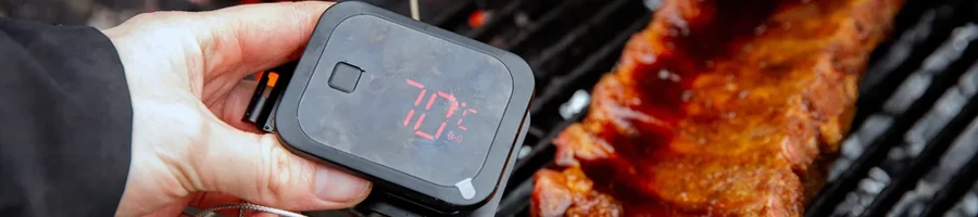 A person monitoring the internal temperature of a meat using a meat thermometer