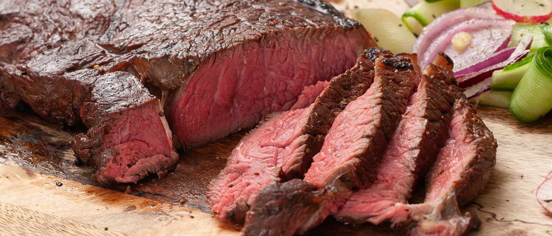 A perfectly cooked top round steak on a wooden board
