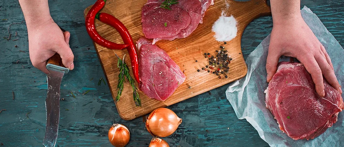 A top view of a person preparing raw meat before cooking
