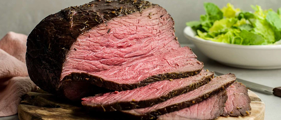 A delicious roast beef sliced on top of a wooden board