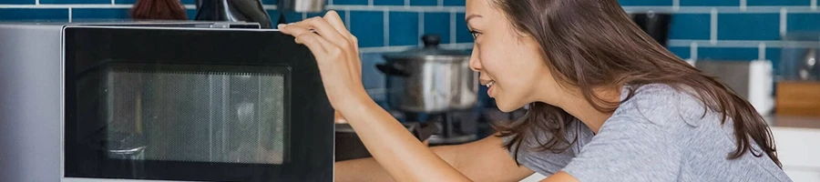 A woman using a microwave to cook a frozen ham