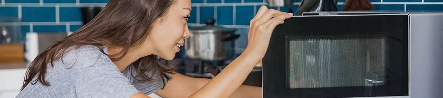 A woman reheating chicken wings using a microwave