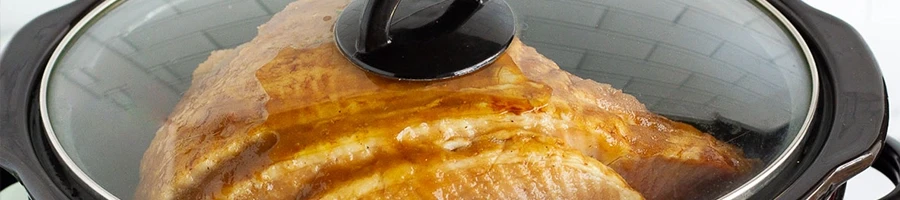 A close up shot of a frozen ham being cooked in a slow cooker