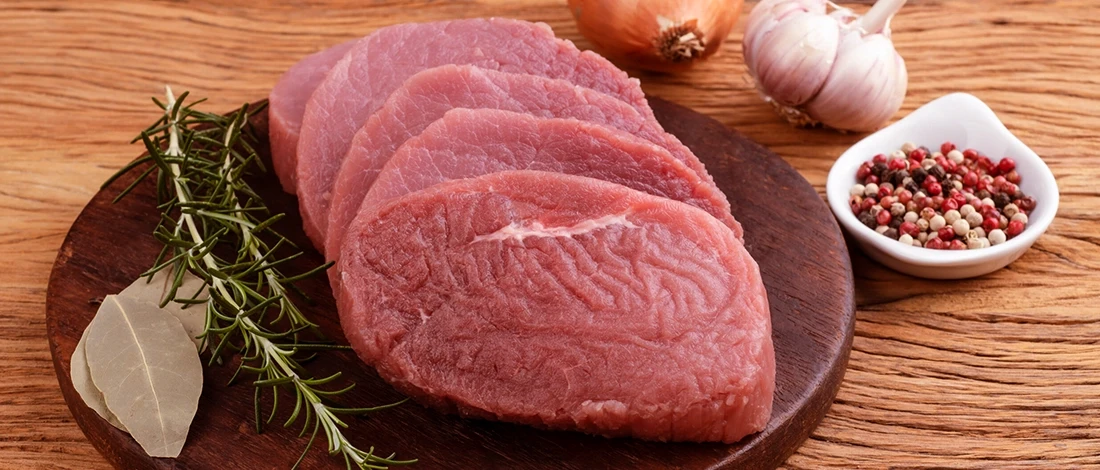 Raw eye of round steak on a wooden board