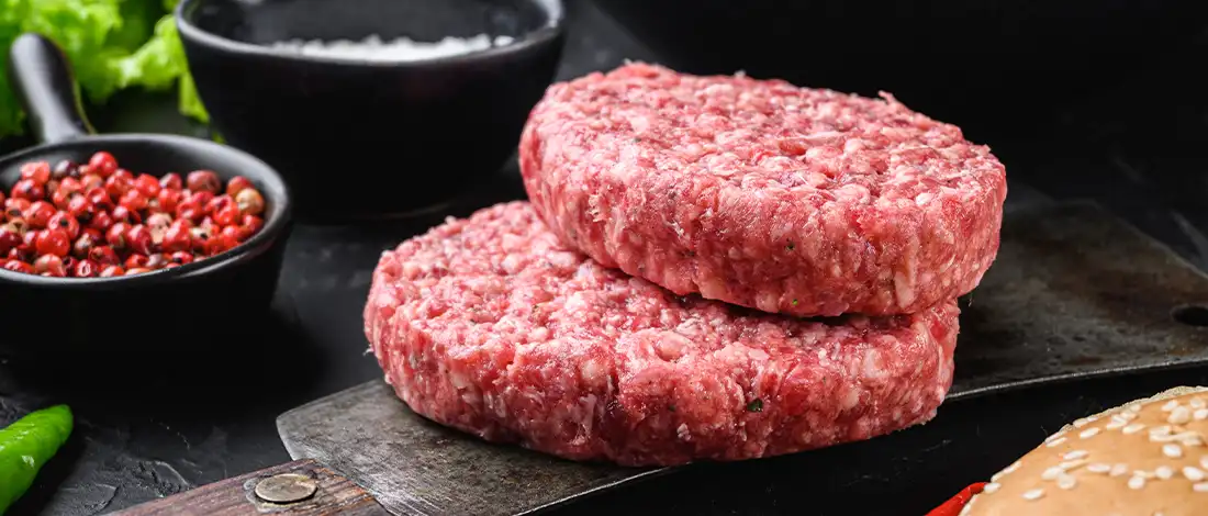 rare hamburger patties on a black slate