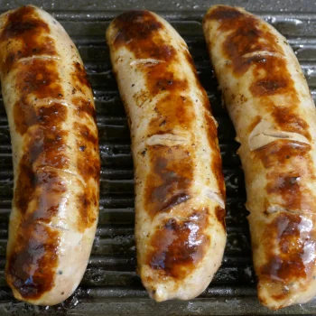 Sausages on a grill shield
