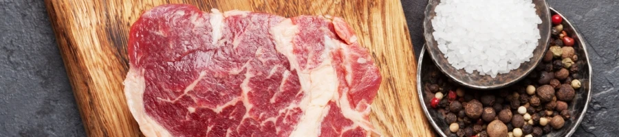 Raw ribeye steak with spices on the side
