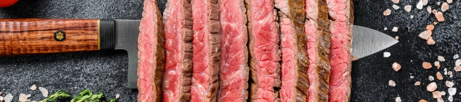 A top view of sliced skirt steak on a knife