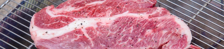 A raw chuck steak on a grill