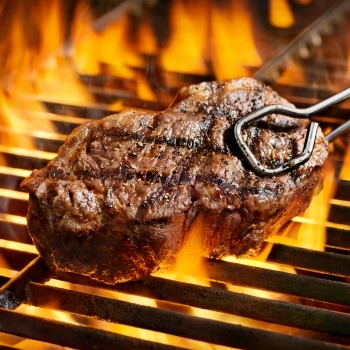 The steak is cooking on a grill.