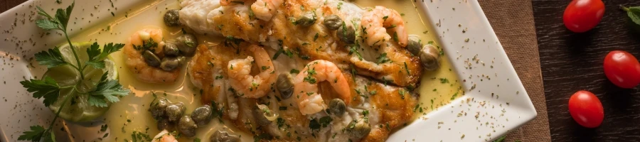 A steak covered with white sauce and some shrimp toppings.