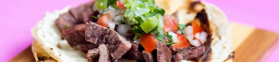 A thin stripped steak with salad on top.