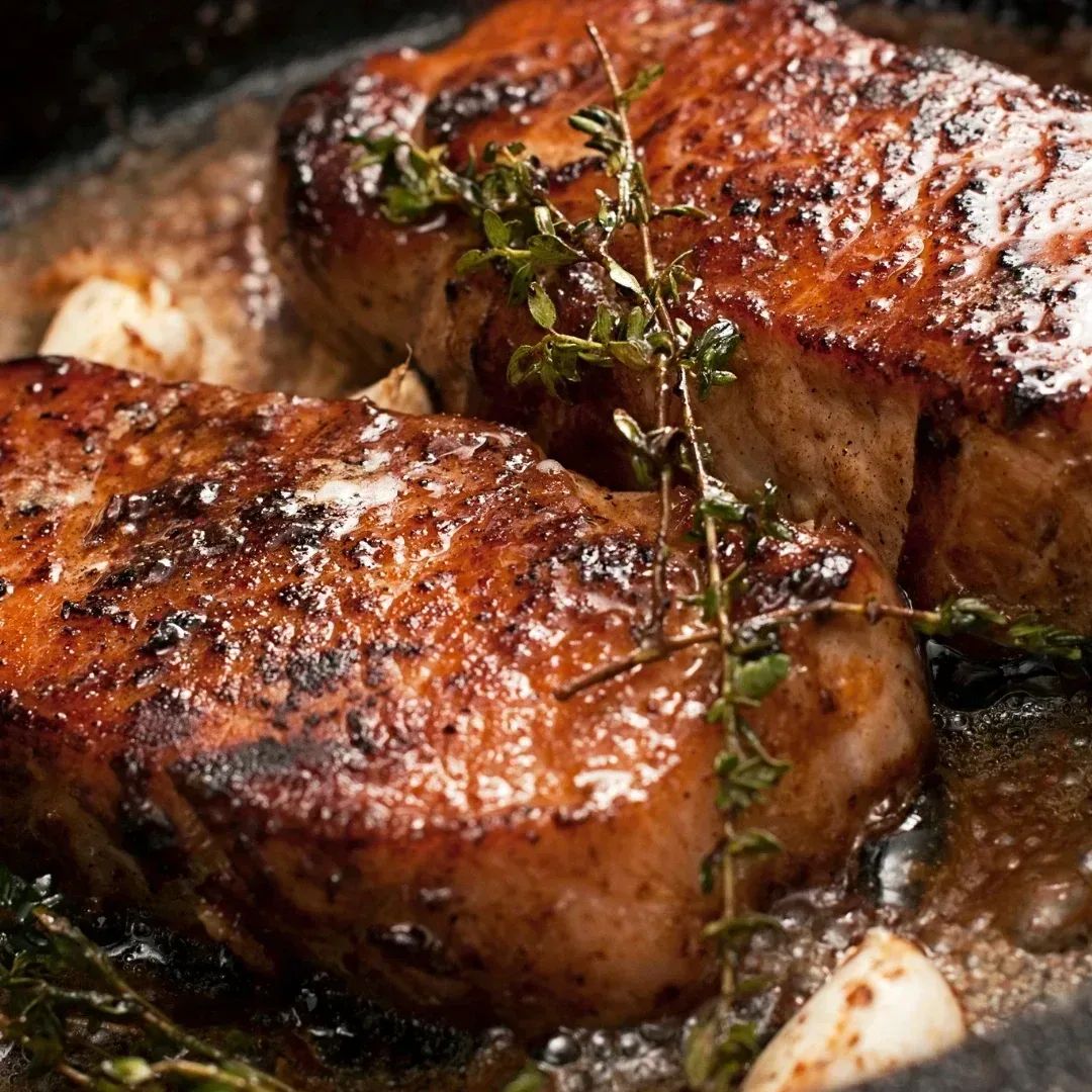 A steak cooking on a pan with lots of butter