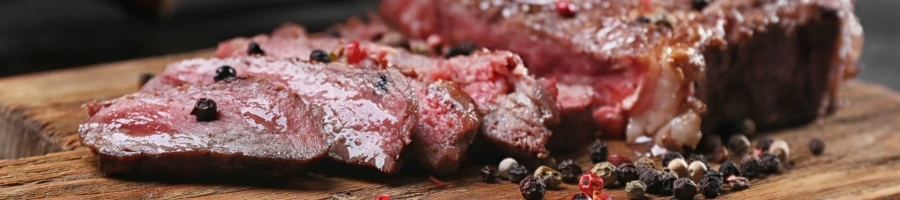 A sliced meat with peppers on top