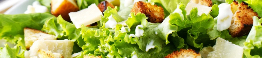 A caesar salad as a side dish for breaded steak sandwich