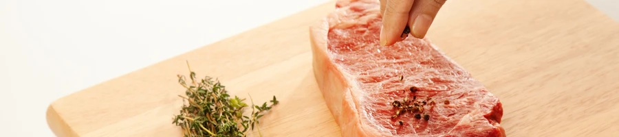 A person seasoning the meat