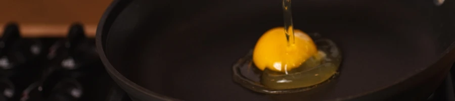 A person cooking an egg on a pan