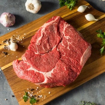 A raw chuck steak on a cutting board