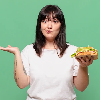 woman shrugging while holding a sandwich