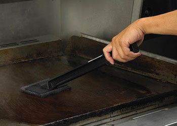 cleaning a dirty grill with a brush