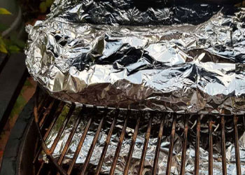 meat wrapped in foil inside a smoker